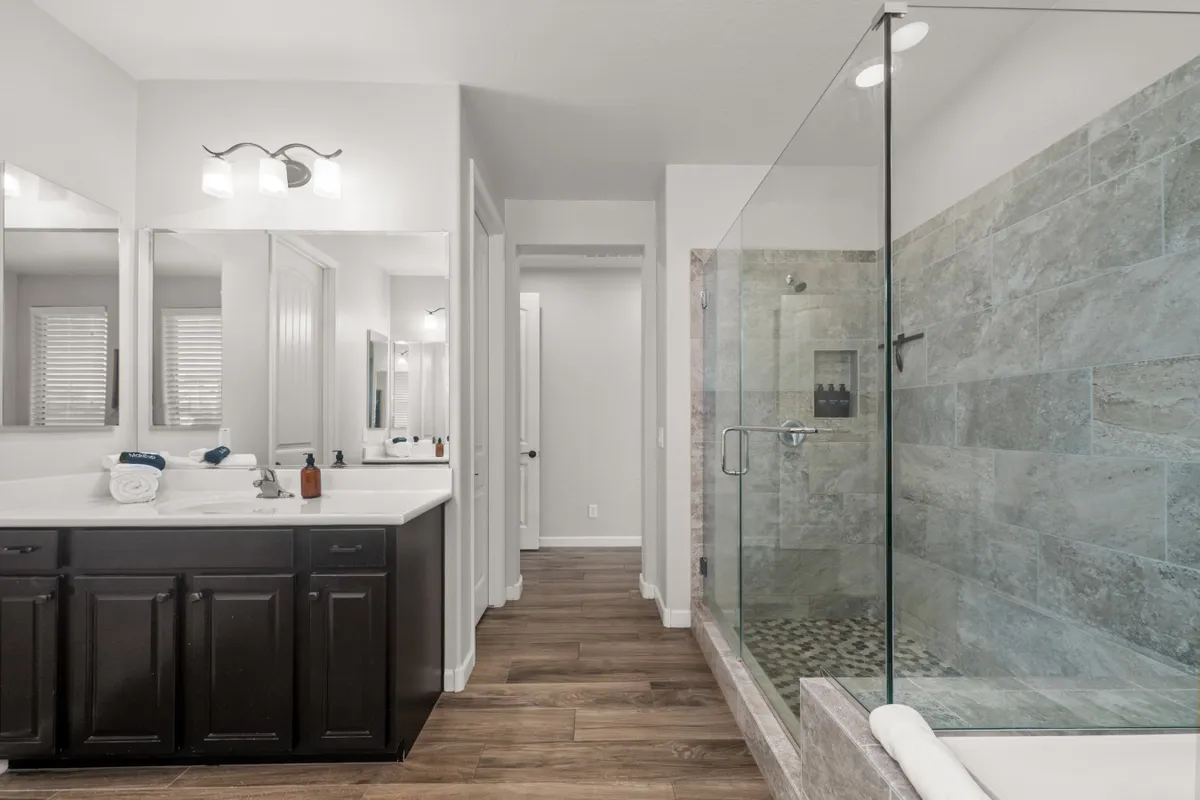 A modern, spa-inspired bathroom with a double sink vanity, glass shower enclosure, freestanding bathtub, and mirrored cabinets. Clean lines, calming colors, and thoughtful lighting create a tranquil, rejuvenating space.