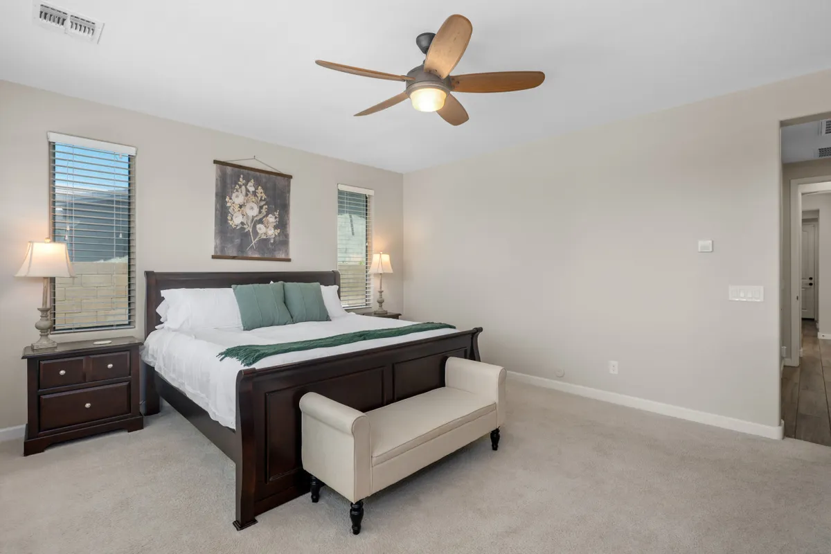 This image features a king-sized bed with crisp linens, elegant nightstands topped with lamps, decorative wall art above the headboard, and a plush bench at the foot of the bed. The atmosphere is serene and comfortable, ideal for restful nights and tranquil mornings.