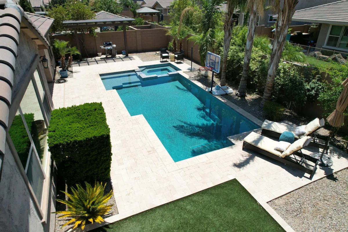 The backyard features a swimming pool with an adjacent hot tub, lounge chairs for sunbathing, and a basketball hoop set against lush greenery. The setup is perfect for both relaxation and active recreation, offering entertainment options beyond the tournament.