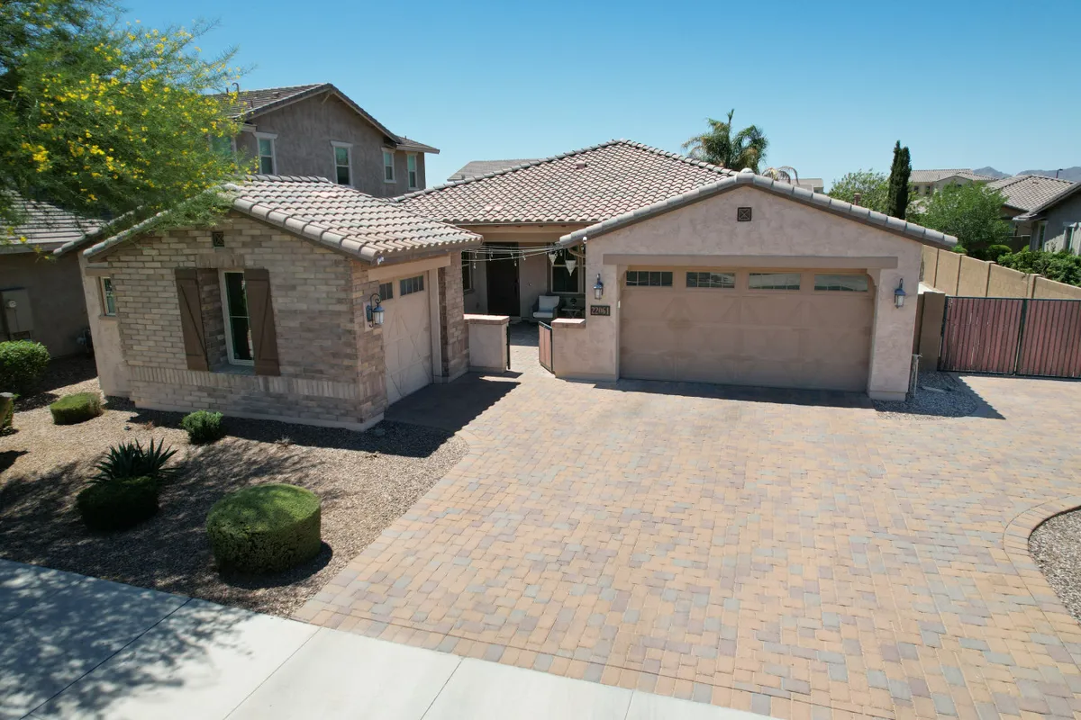 A view of the home's brick exterior, featuring a landscaped front yard, paved driveway, garage door, and welcoming front porch. The scene exudes an inviting, lived-in atmosphere typical of a peaceful suburban neighborhood.