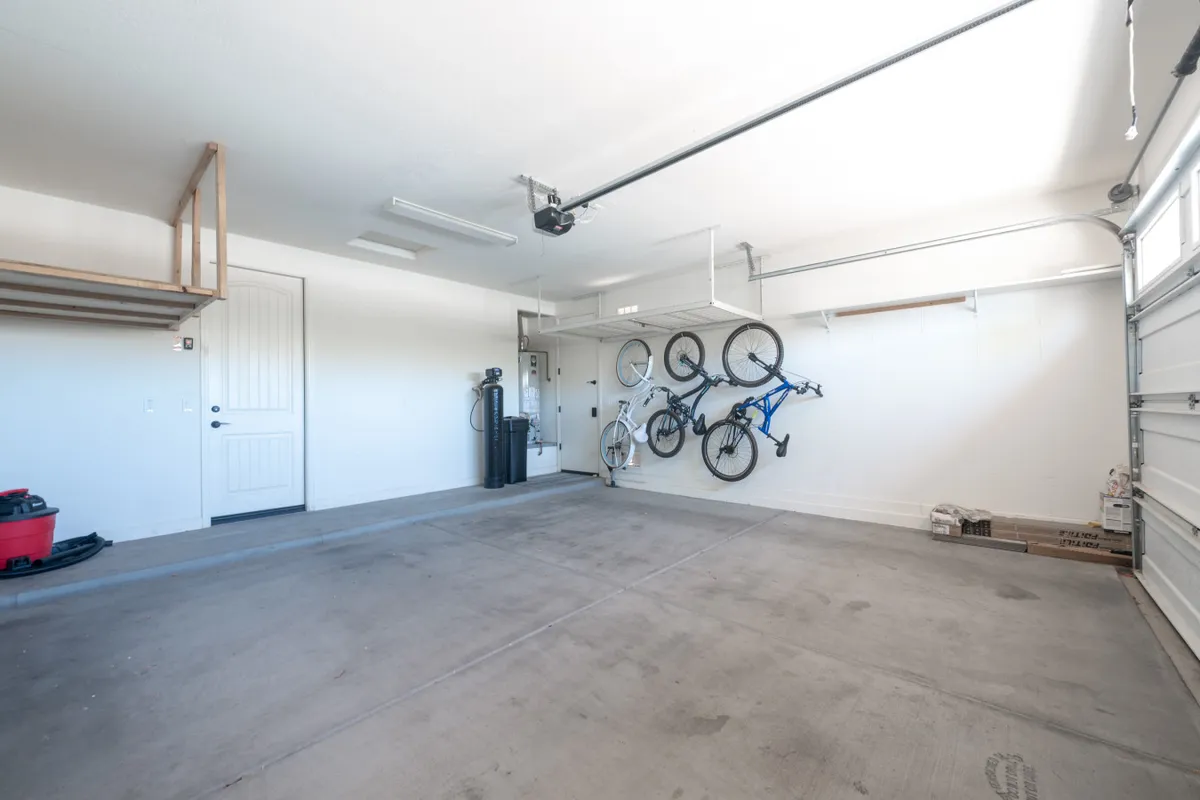 Inside the garage, several bicycles are mounted on the wall alongside storage shelves and the garage door. The area is organized, highlighting the availability and convenience of bikes for guest use.