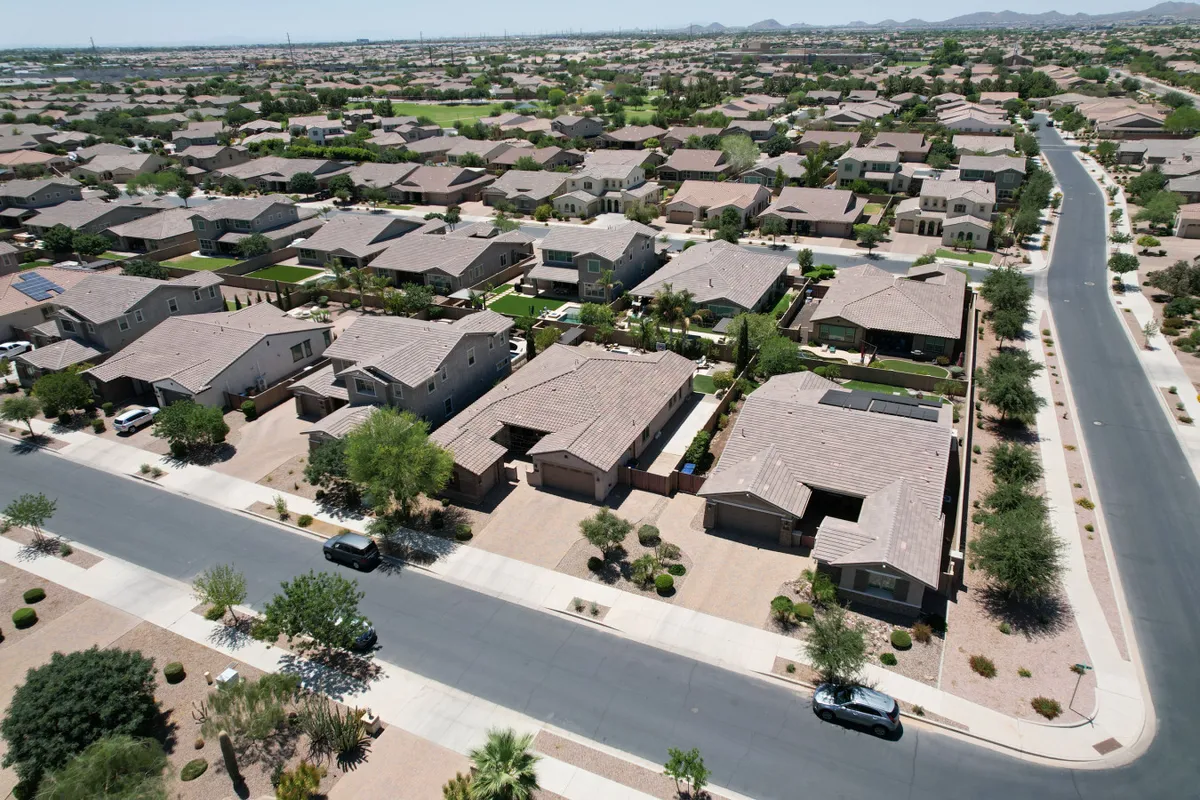 A view of the peaceful, well-kept neighborhood with neatly trimmed lawns, palm trees, and residential homes. The wide, paved roads hint at quiet walks or bike rides as the sun sets, reinforcing the sense of privacy and community.